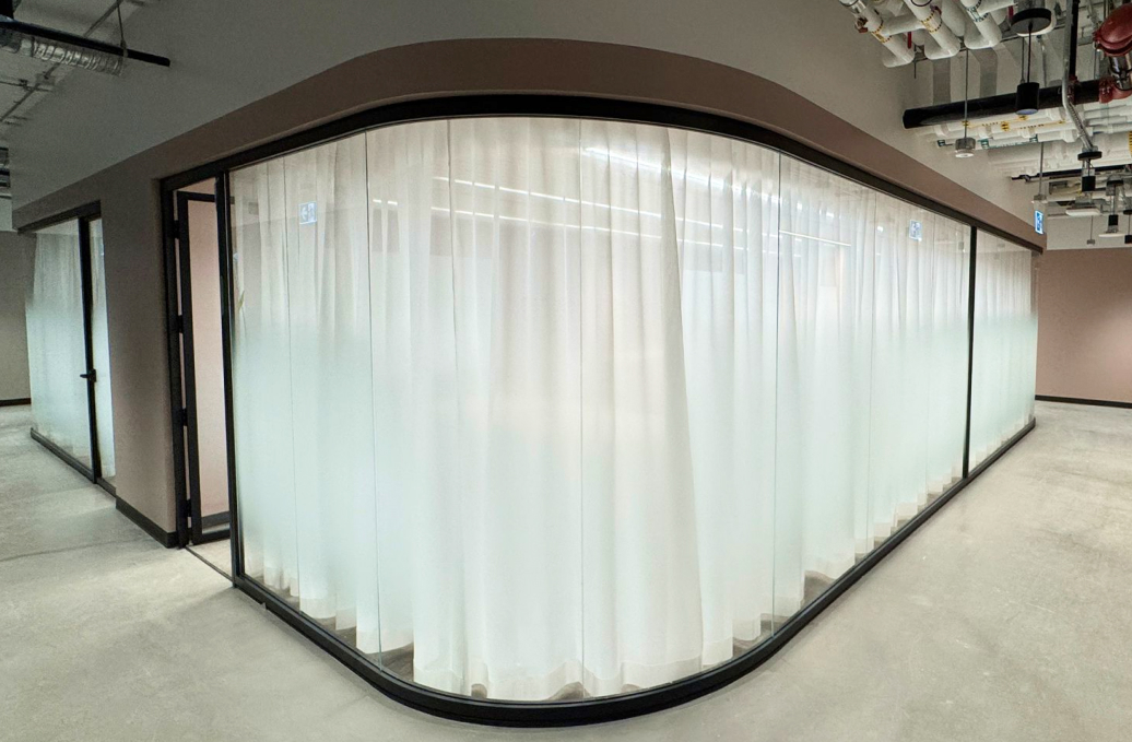 alt="Movable curved glass walls installed by Systemax in modern office space."