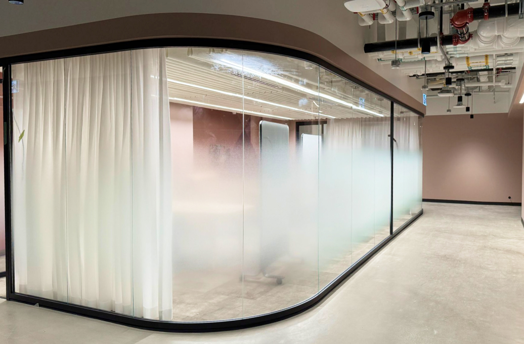 alt="Movable curved glass walls installed by Systemax in modern office space."