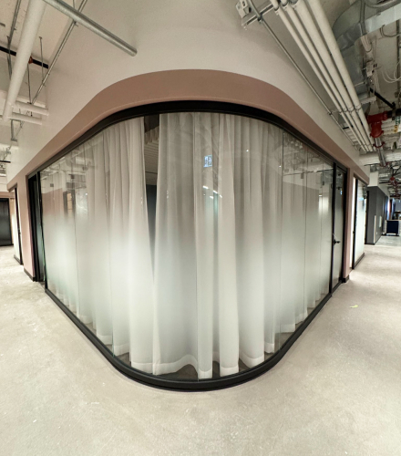 alt="Movable curved glass walls installed by Systemax in modern office space."