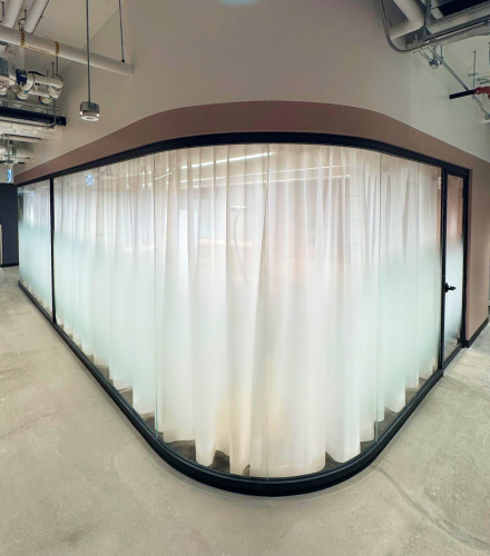 alt="Movable curved glass walls installed by Systemax in modern office space."